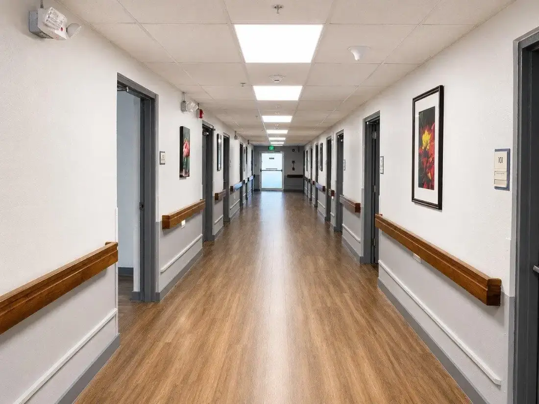 Bright, wide hallway with handrails and wood floors