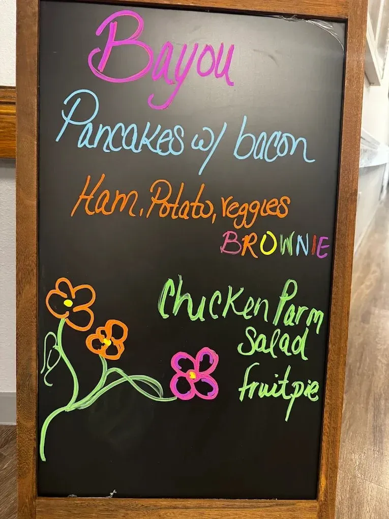 Hand-drawn chalkboard with the day’s menu: pancakes with bacon, ham, potato and veggies, brownie, chicken parm, salad and fruit pie